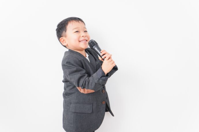 画像：マイクを持ち得意げなスーツの男の子