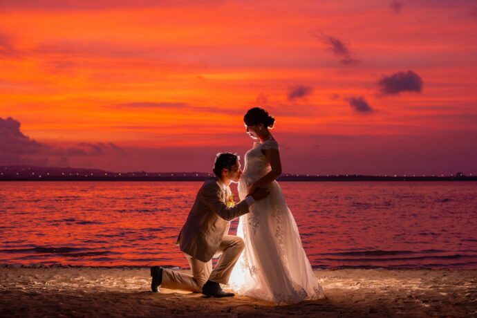 画像：ビーチで妊婦のお腹にキスをする花婿