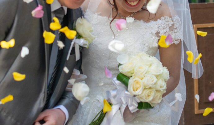 画像：花びらが舞う中進む新郎新婦