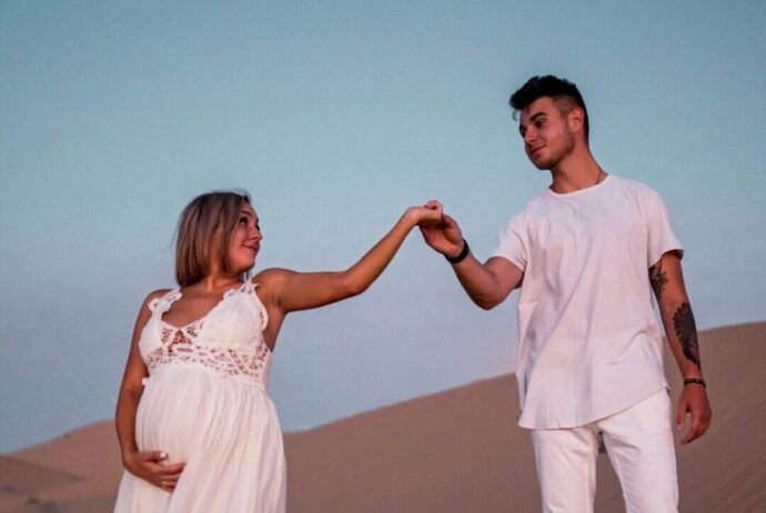 画像：白いワンピースの妊婦の手を取る男性