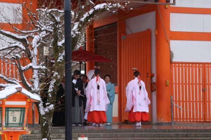 画像：神社の門で待機する新郎新婦と巫女
