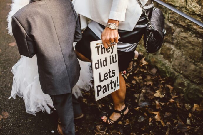 画像：They did it! let's party! と書かれた看板を持った男性の後ろ姿