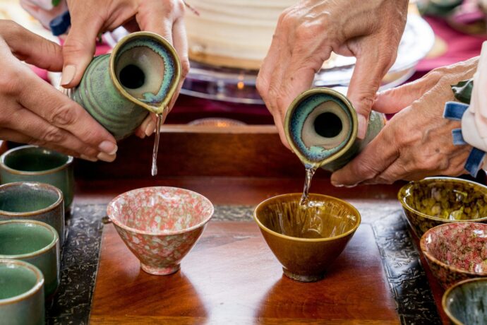 画像：2つの徳利から2つのおちょこにお酒を注いでいる