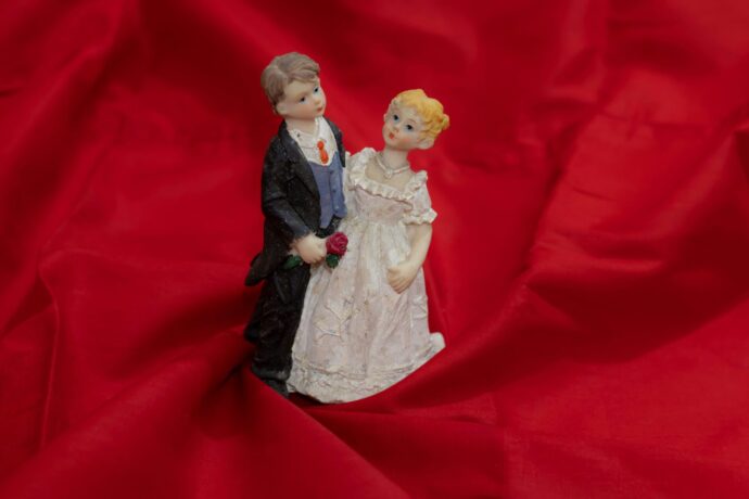 画像：赤い布の上で寄り添う花嫁と花婿の人形