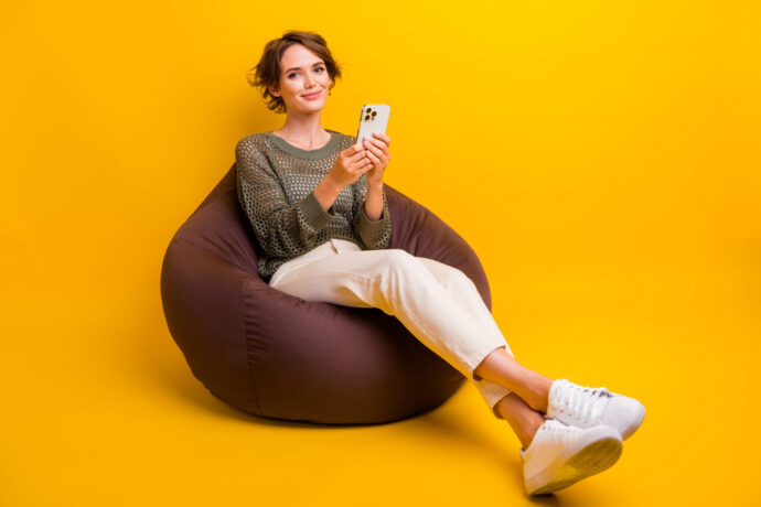 画像：ビーズクッションに座ってスマホを操作する女性