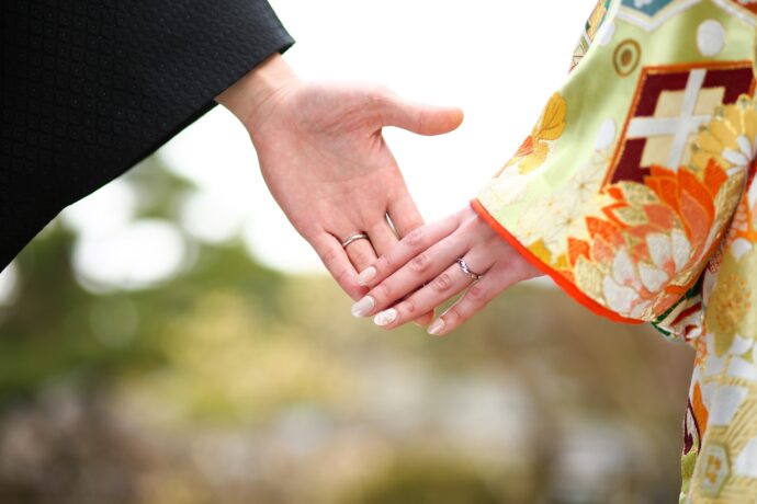 画像：結婚指輪を着けた手を重ねる和装の新郎新婦