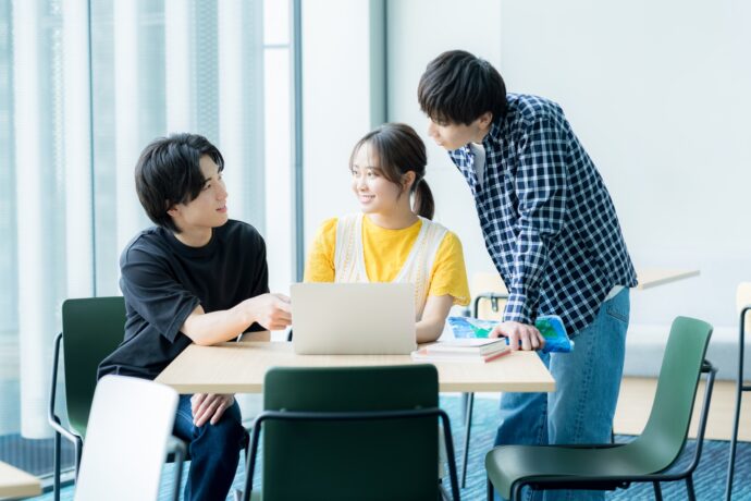 画像：パソコンを囲んで話し合う若い男女