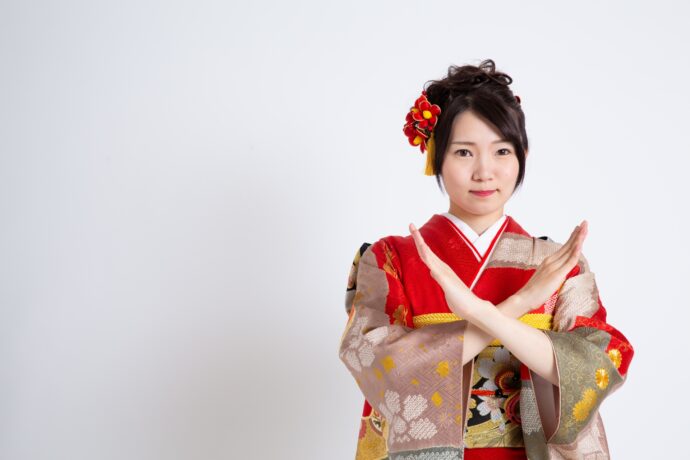 画像：体の前でバツを作る振袖の女性