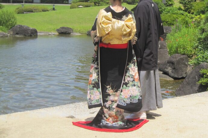画像：黒引き振袖を着て日本庭園に立つ花嫁と花婿
