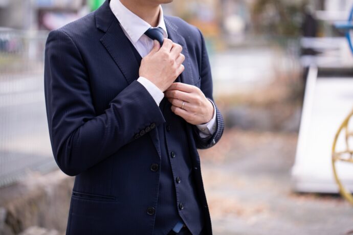 画像：ネクタイを締め直すスーツの男性