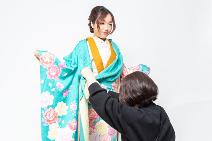 画像：振袖を着つけてもらっている女性