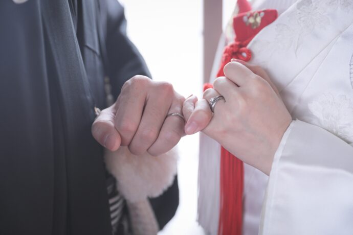 画像：向き合って左の小指を絡ませた和装の新郎新婦