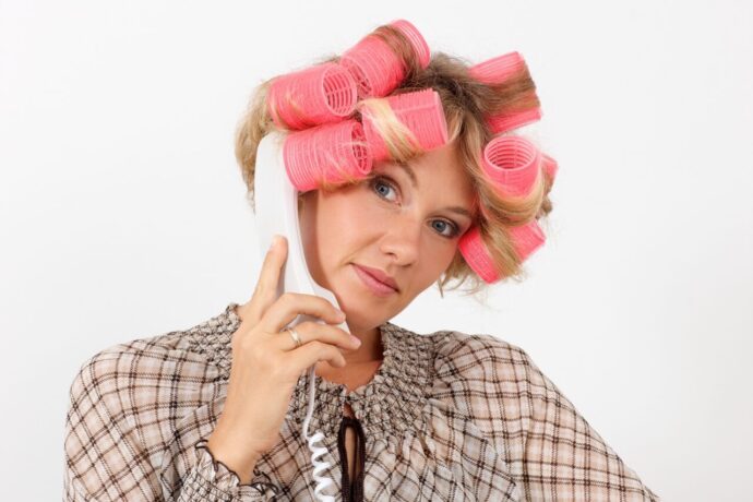 画像：ヘアカーラーを毎て受話器を耳に当てる女性