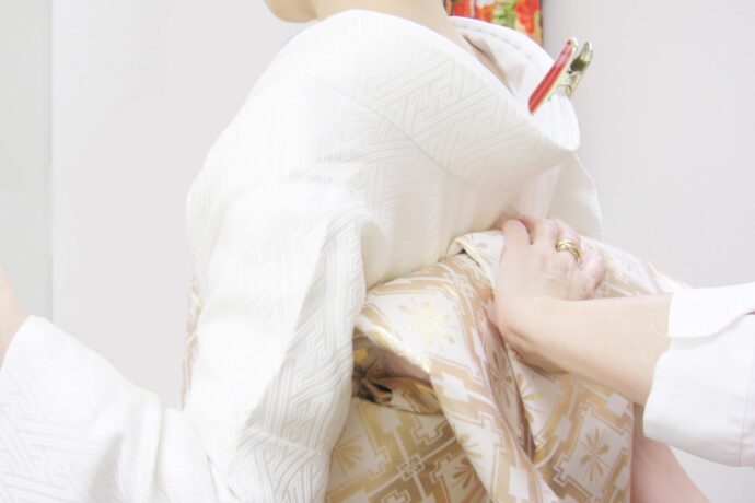 画像：振袖を着つけてもらっている女性