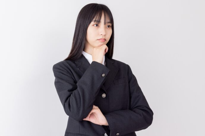 画像：顎に手をあて腕を組む女子高生