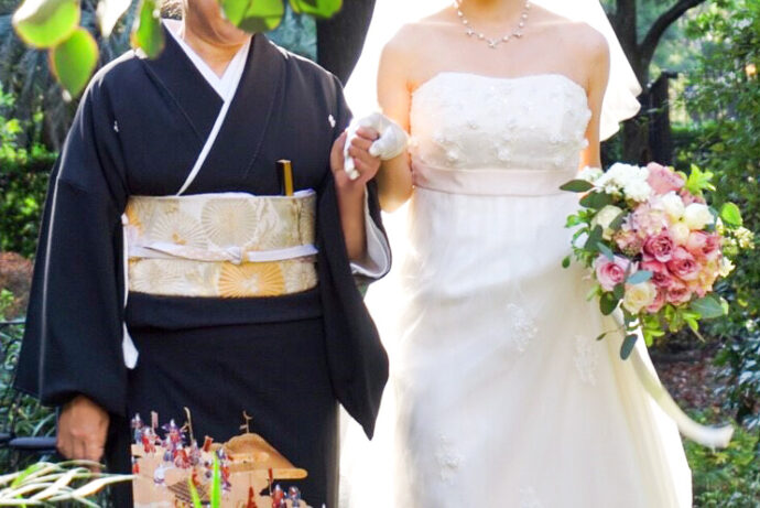 画像：黒留袖の母親と手を繋ぐ花嫁