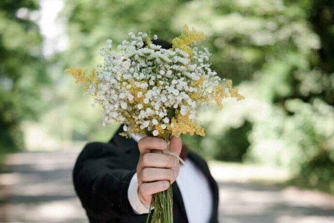 画像：花束をこちらに差し出し顔を隠す男性