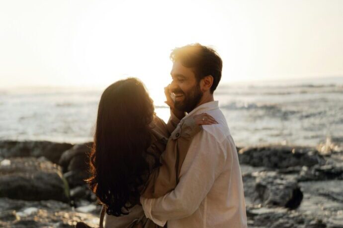 画像：夕日の中抱き合って笑いあう男女