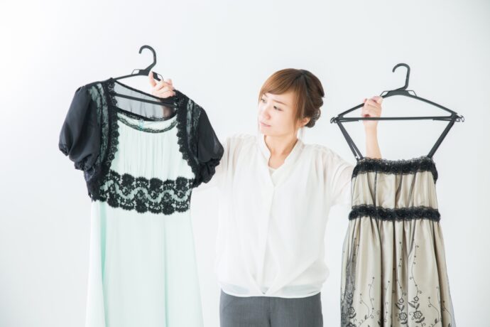 画像：両手にドレスを持った女性