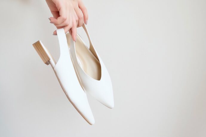 画像：白いパンプスを手に持っている