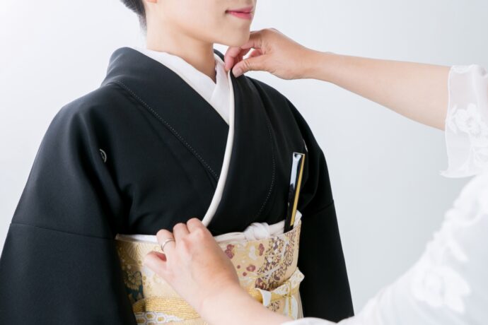 画像：黒留袖を着つけてもらっている女性
