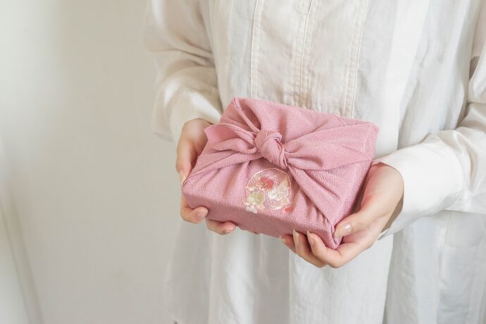 画像：ピンクの風呂敷を差し出す女性