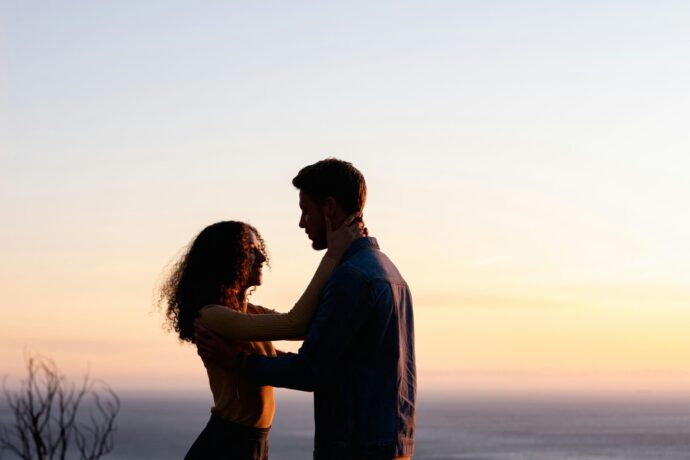 画像：夕日に照らされてシルエットになった男女
