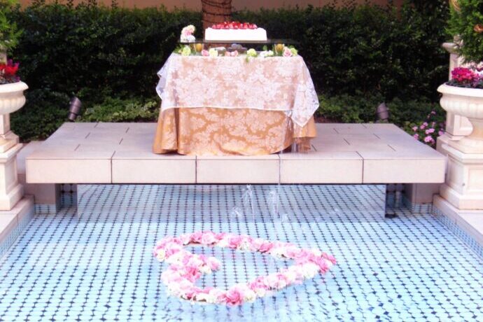 画像：プールサイドのウエディングケーキとプールに浮かぶハートの装花