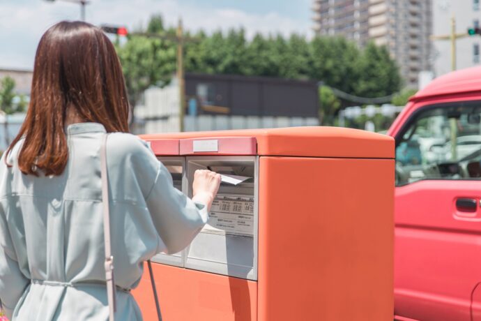 画像：ポストに投函する女性