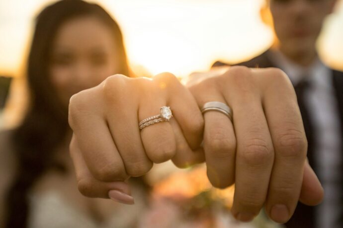 画像：婚約指輪と結婚指輪はめてこちらに拳を突き出す男女