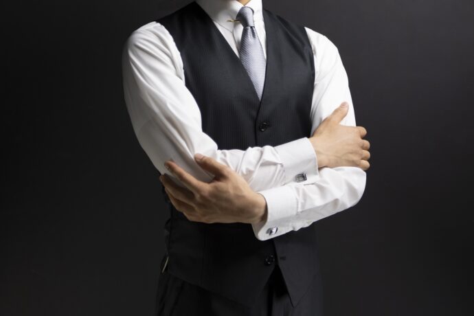 画像：腕組みするベストの男性
