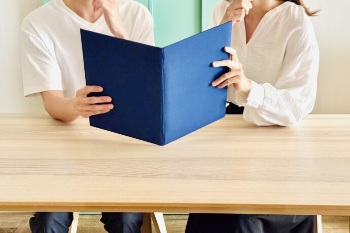 画像：冊子を覗き込む男女