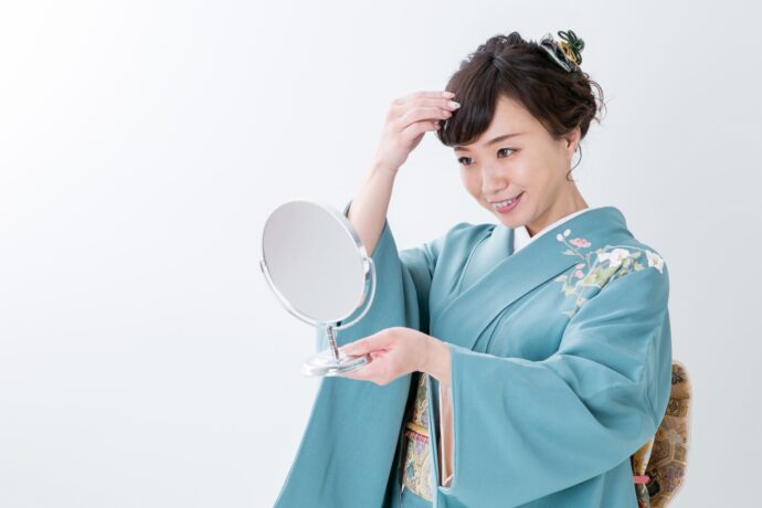 画像：前髪を直す水色の着物の女性