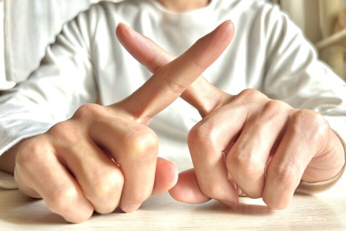 画像：指でばつを作る男性