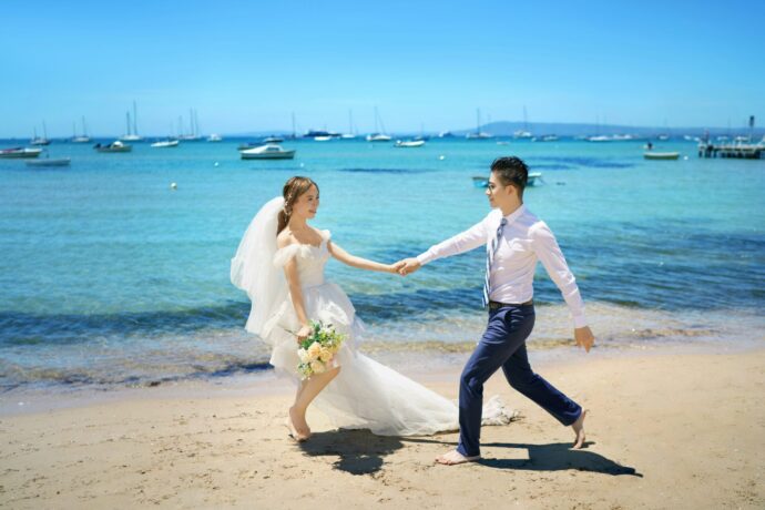 画像:新郎の手を引いて砂浜を歩く新婦