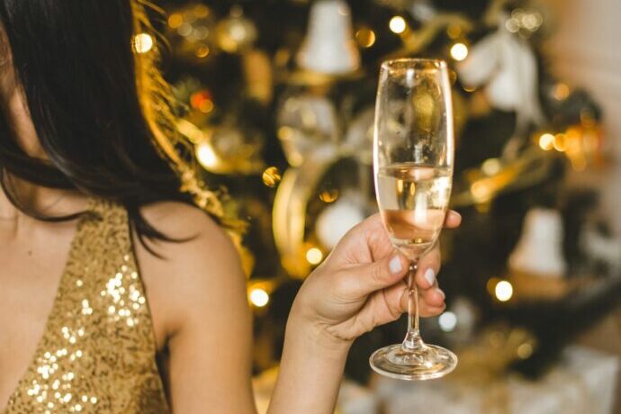 画像:シャンパンを持ったゴールドスパンコールのドレスを着た女性