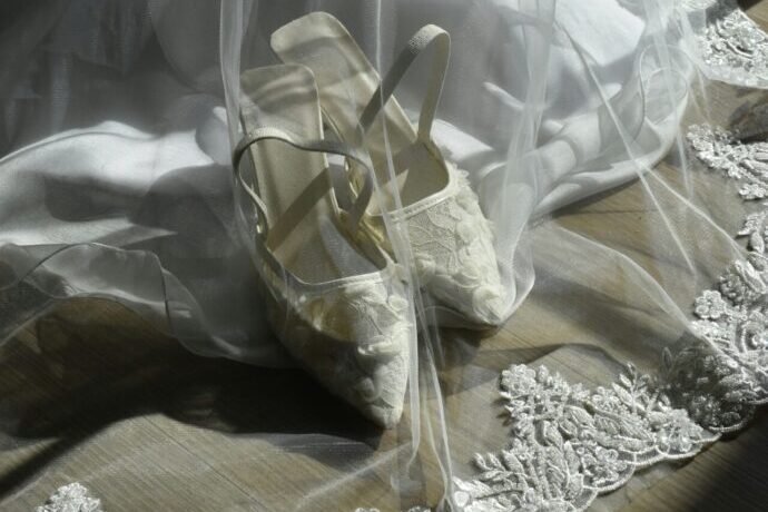 画像：ウエディングドレスのベールに包まれたブライダルシューズ