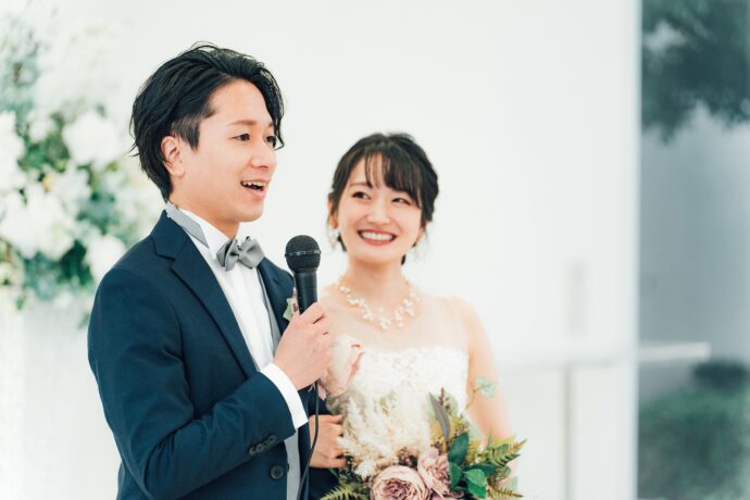 画像：マイクを持ち話す新郎を見つめる新婦