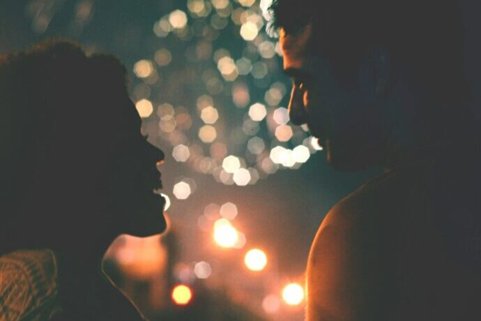 画像:打ち上げ花火を背景にシルエットになった男女