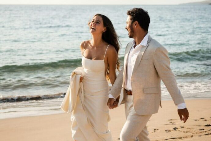 画像:手を繋いでビーチを歩く花嫁と花婿