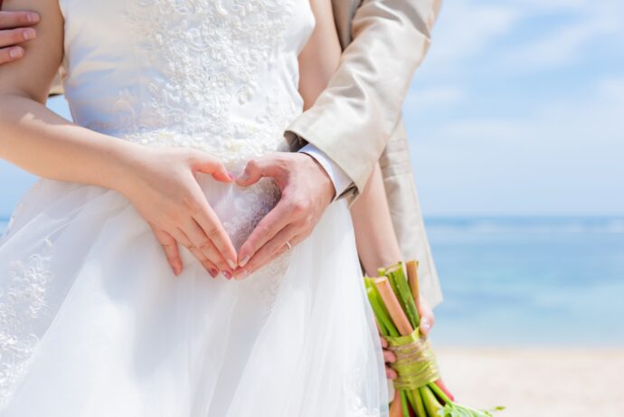 画像:お腹の前でハートマークを作ったウエディングフォト