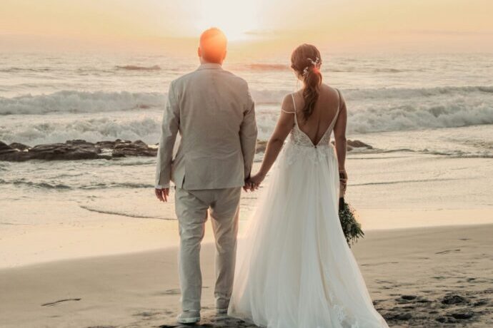 画像:波打ち際で手を繋ぐ新郎新婦