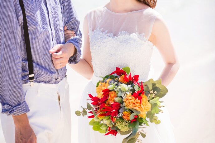 画像:砂浜で腕を組む新郎新婦