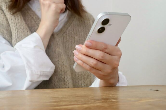 画像:スマホを見て考え込む女性