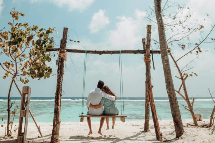 画像：砂浜のブランコで肩を寄せ合う男女