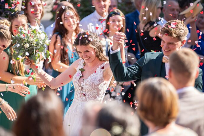 画像：コンフェッティシャワーの中歩く新郎新婦