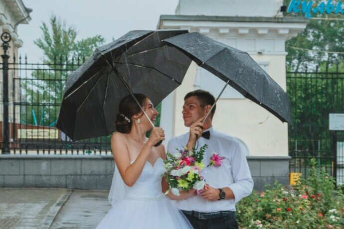 画像：雨の中傘を差す新郎新婦