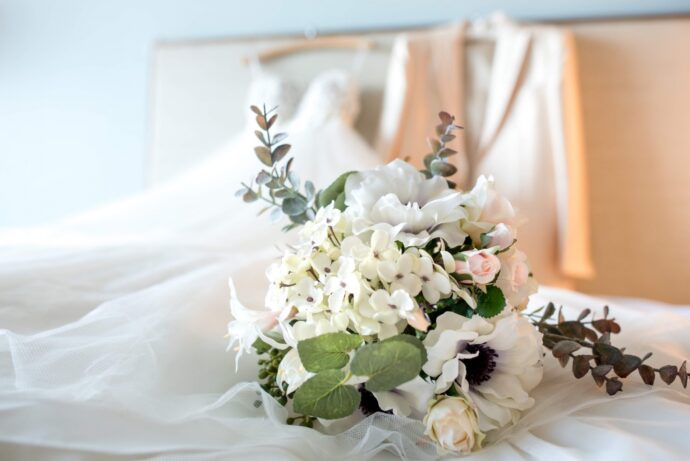 画像：ベッドの上の婚礼衣裳とブーケ
