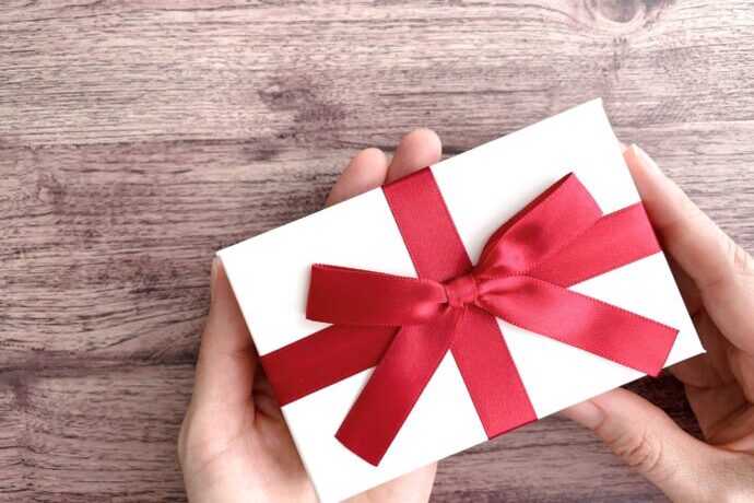 画像：赤いリボンのかかった箱を持つ両手