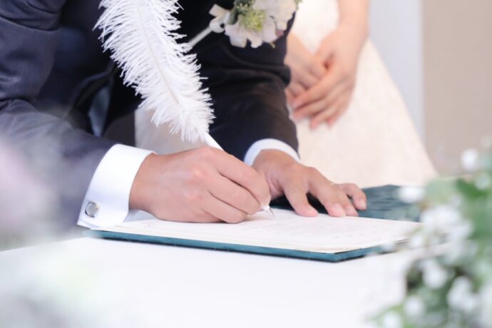 画像：結婚証明書にサインする新郎